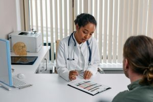 A doctor consulting with a patient in an office, discussing a medical chart. Red light therapy has many benefits.