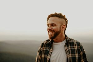 a man with dreadlocks smiles at the camera